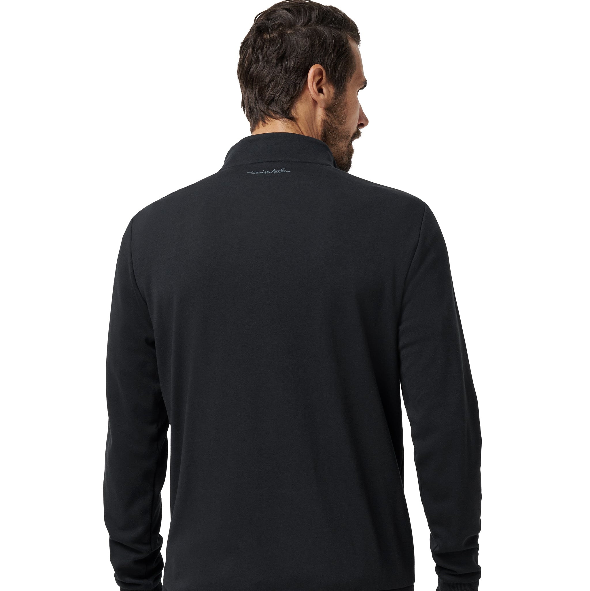A man viewed from the back wearing a black long-sleeve quarter-zip pullover sweater and gray jeans, set against a plain white background.