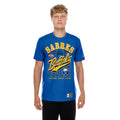A young man modeling a blue short-sleeve graphic T-shirt with 'SABRES Buffalo' in yellow and white lettering, paired with black pants, against a plain white background.