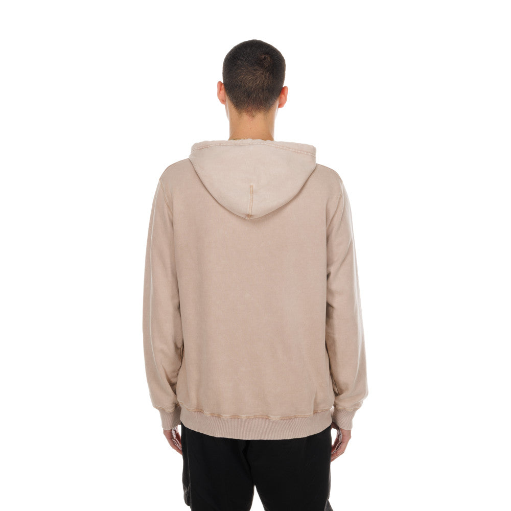 A man viewed from behind wearing a light beige hooded sweatshirt and black pants, set against a plain white background.