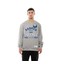 A man modeling a heather gray crewneck sweatshirt with a blue and white Buffalo Sabres graphic on the chest, paired with black pants against a solid white background.