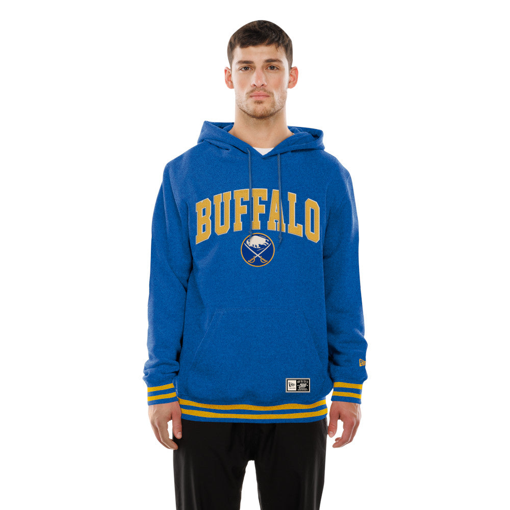 A man wearing a blue Buffalo hooded sweatshirt with yellow and white lettering and stripes, paired with black pants, against a plain white background.