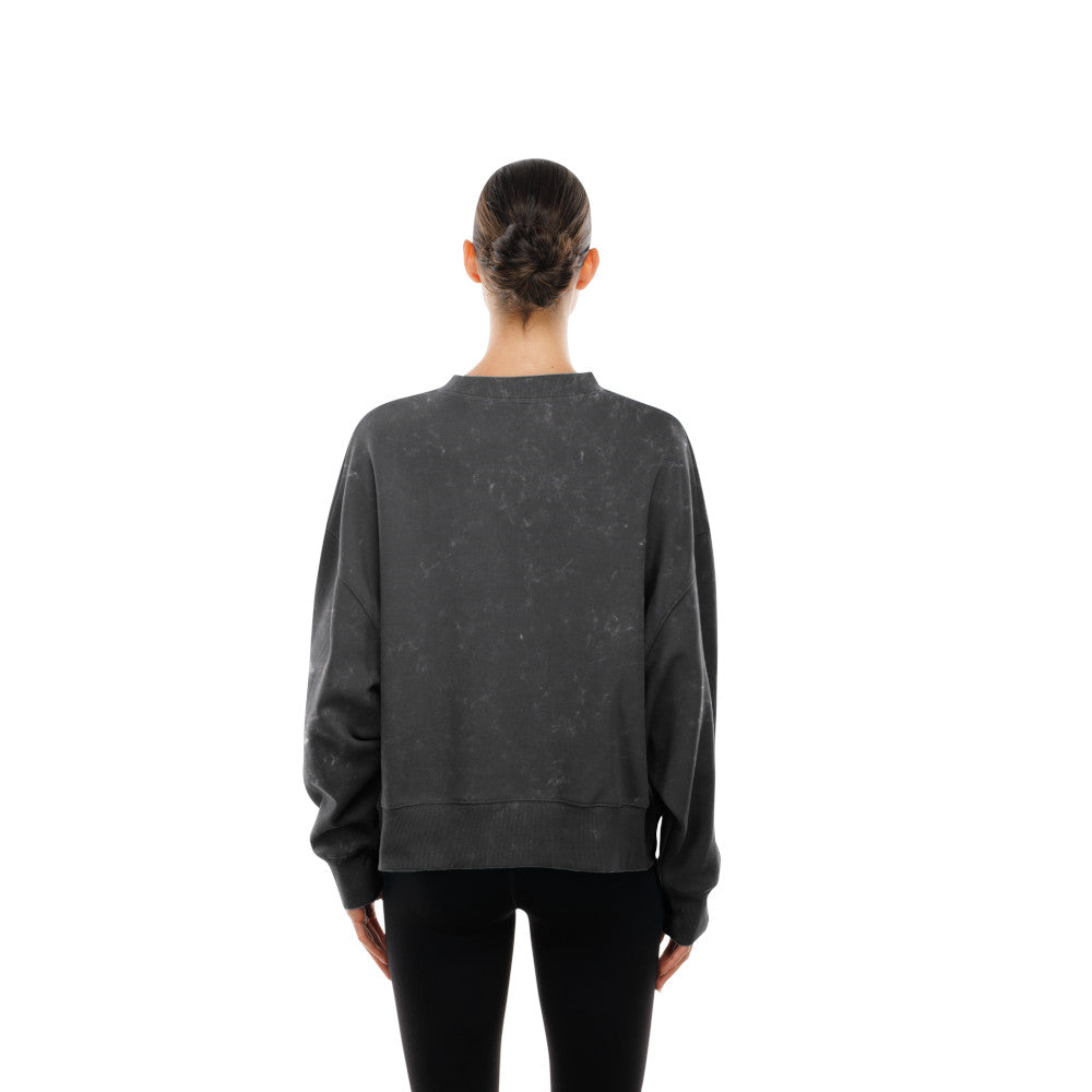 A person viewed from the back wearing a dark charcoal gray washed crewneck sweatshirt and black pants, set against a plain white background.