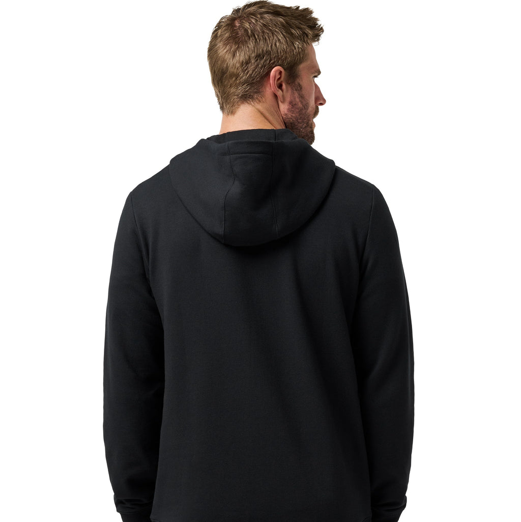 A man viewed from the back wearing a plain black pullover hoodie and light gray pants against a clean white background.