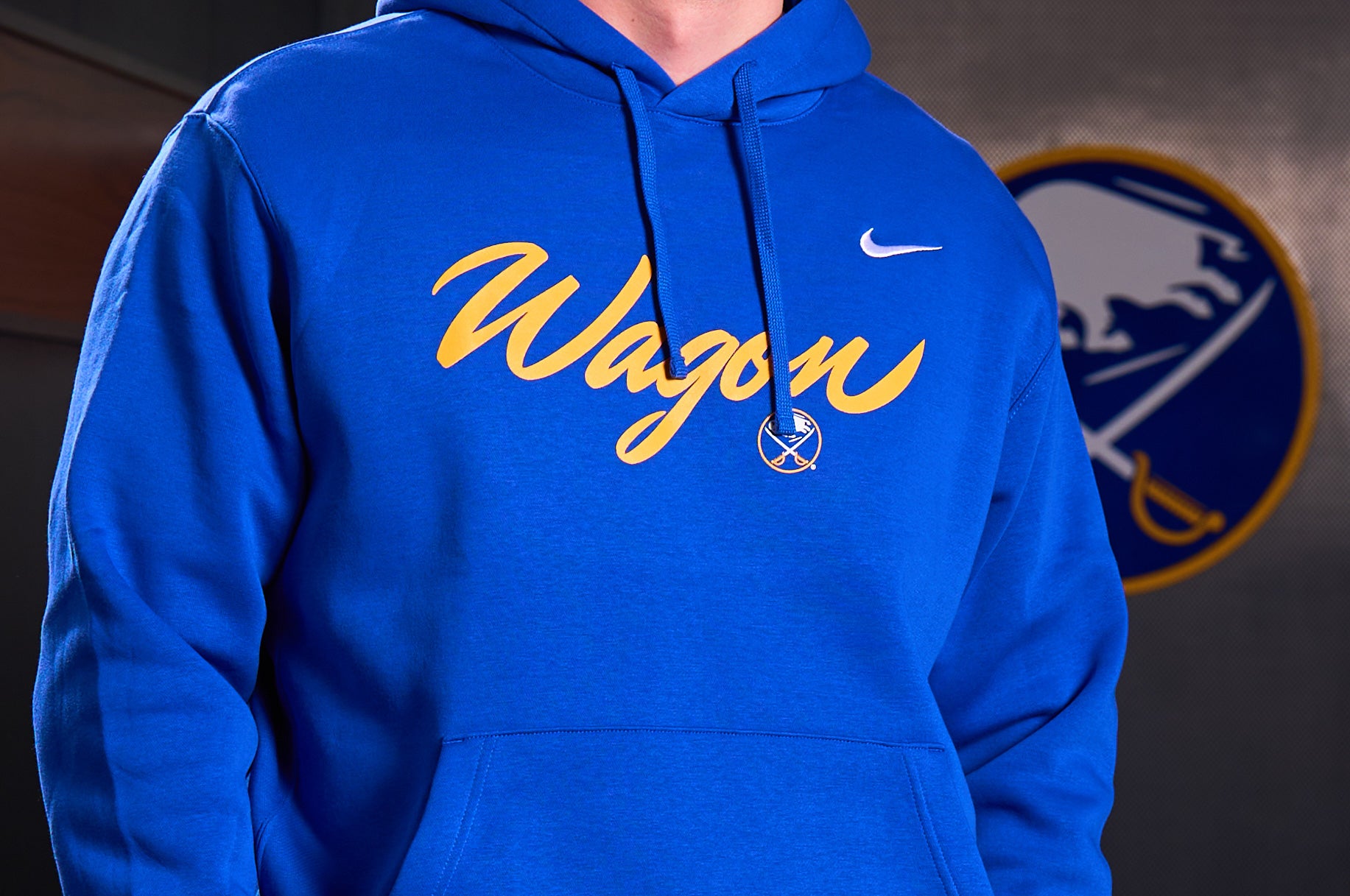 Blue hoodie with 'Wagon' text and Nike logo, worn by a person, with a blurred background.